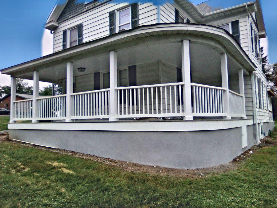 Curved porch with white railing and parged skirt